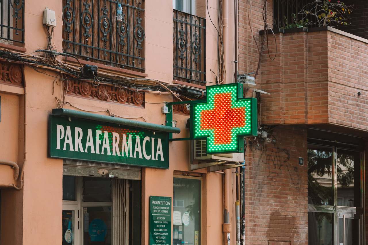 Green cross pharmacy sign on a street in southern Europe